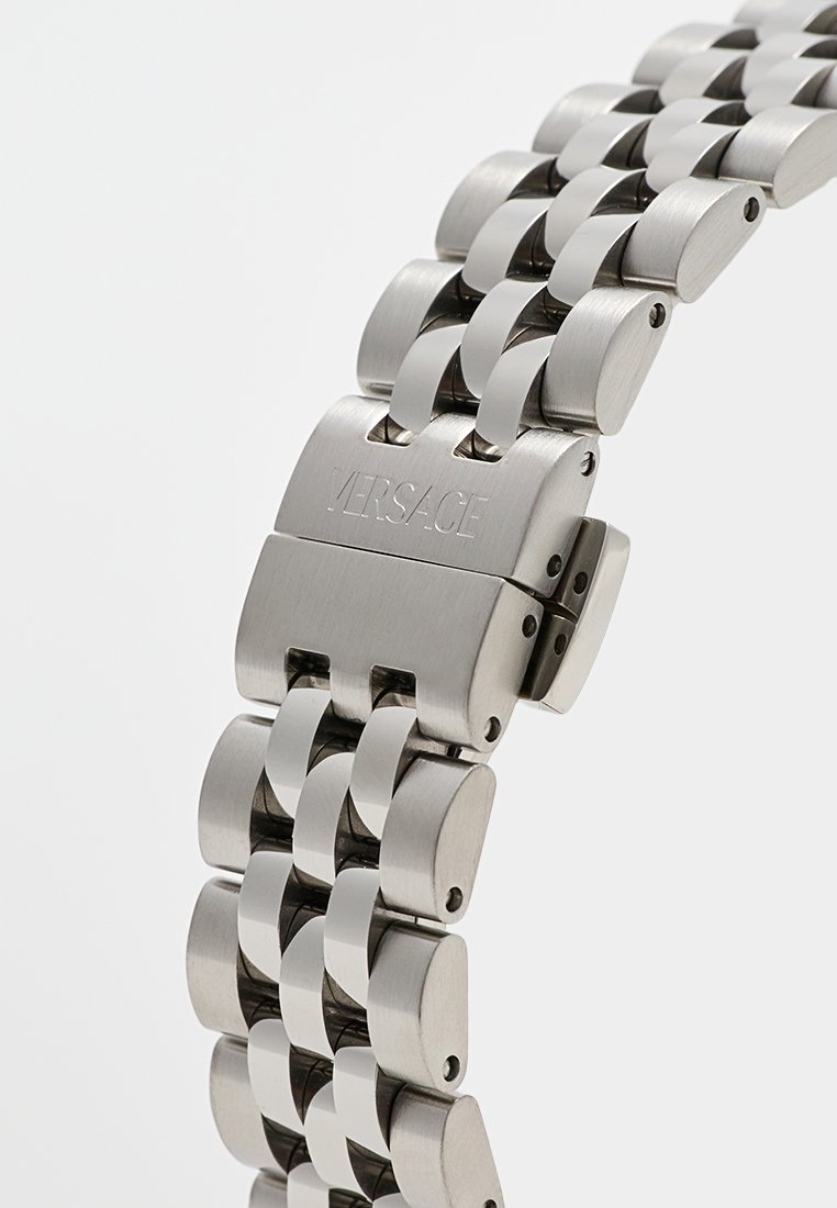 Bracelet de montre en acier inoxydable argenté avec des maillons emboîtés et une finition polie. Présente un fermoir marqué "Versace". Design simple et épuré.