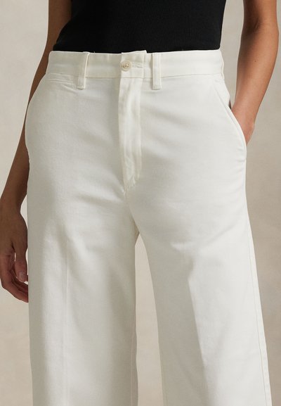 Białe spodnie o szerokich nogawkach wykonane z bawełny, z zapięciem na guziki z przodu, bocznymi kieszeniami i gładką fakturą.