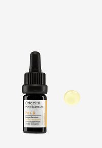 Odacité Papaya-Geranium serum i en svart glassdråpeflaske med gule detaljer. En dråpe med gul serum ligger ved siden av flasken.