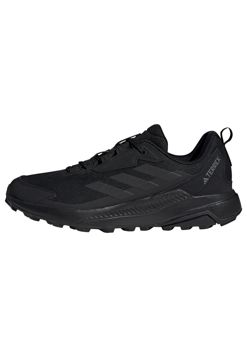 Chaussure de sport noire avec un dessus en maille, des superpositions texturées et une semelle en caoutchouc. Elle dispose de lacets et d'un talon renforcé pour un meilleur soutien.