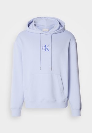 Svetlomodrá bavlnená mikina s predným vreckom, kapucňou na šnúrku a potlačeným logom na hrudi. Mäkká textúra a voľný strih.