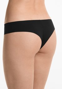 Zwarte bikini-bh met een gladde textuur, ontwerp met minimale bedekking en strakke lijnen, weergegeven in een zijaanzicht tegen een neutrale achtergrond.