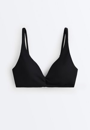 Bralette in tessuto nero texturizzato con sottili spalline regolabili e dettaglio frontale annodato su sfondo bianco.