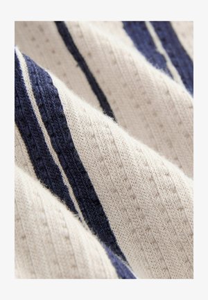 Nertinis megztinis su horizontaliomis juostelėmis tamsiai mėlynos ir grietinėlės spalvų, su tekstūruotu raštu ir minkštu, pūkuotu paviršiumi.