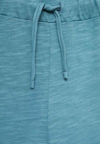 Teal drawstring sweatpants featuring a textured fabric, soft finish, and adjustable waistband with evenly spaced thread stitching.
