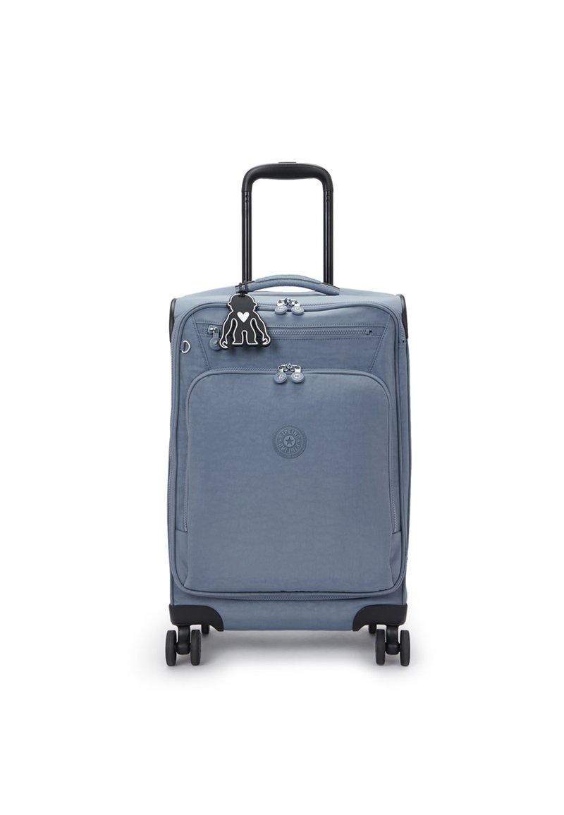 Modrý měkký kufr se skládacími madly, čtyřmi kolečky, přední kapsou na zip a připevněným černým klíčenkou s postavou.