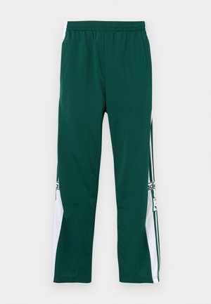 Grønne treningsbukser med elastisk midjebånd, med hvite sidepaneler og en logo. Stoffet har en glatt, lett tekstur.