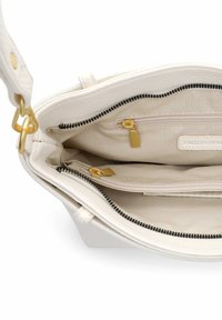 Balta ādas soma ar bēša oderējumu, divām kabatām ar rāvējslēdzēju un zelta detaļām. Aprīkota ar rāvējslēdzēja aizdari un gludu tekstūru.