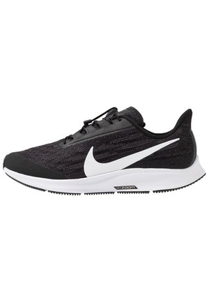 Zapatilla de correr negra Nike con logo swoosh blanco, suela blanca y tecnología de amortiguación Zoom Air, mostrada de perfil.