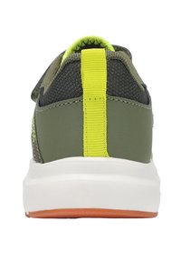 Rückansicht eines grünen Sneakers mit einer gelben Fersenschlaufe, weißer Zwischensohle und strukturiertem schwarzem Material im Oberteil. Gummilaufsohle mit orangefarbener Akzentuierung.