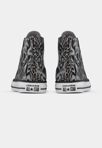 Tenisi Converse înalte cu un model de imprimeu animal gri și negru, talpă din cauciuc albă și branding negru pe călcâie.