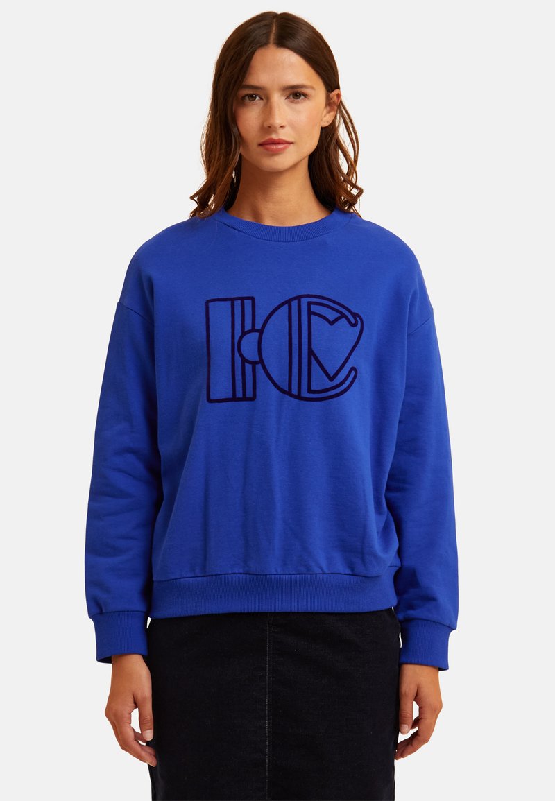 Blaues Baumwoll-Sweatshirt mit einem großen schwarzen Grafikdesign auf der Vorderseite, rundem Ausschnitt und gerippten Bündchen und Saum.