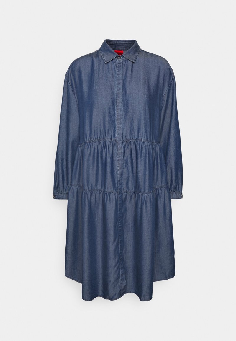 Robe-chemise longue manches bleue en denim, longueur genou, taille froncée, boutonnée sur le devant avec col pointu sur fond uni.