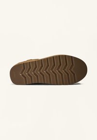 Brown rubber sole with zigzag tread pattern, featuring textured surface for grip and stability. Rounded toe and slightly raised edges.