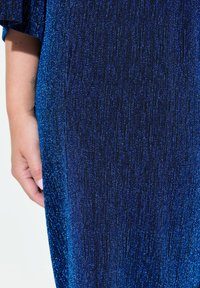 Vestito blu realizzato in tessuto testurizzato, con una sfumatura che va dal blu scuro al blu chiaro, con una finitura scintillante e sottili strisce verticali.