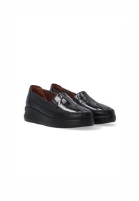 Černé kožené slip-on boty s lesklým povrchem, kontrastním prošíváním a nízkou gumovou podrážkou. Interiér má hnědou podšívku.