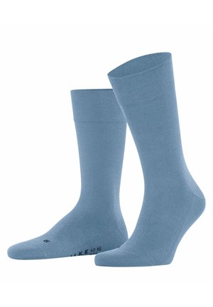 Een paar effen lichtblauwe sokken tot halverwege de kuit met verstevigde tenen en boorden, rechtopstaand getoond op een witte achtergrond.