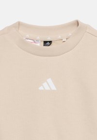 Bež pulover z okroglim izrezom in bež ovratnikom, na sredini pod ovratnikom bel logotip Adidas, rebrast izrez.