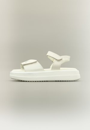 Sandalo platform bianco con cinturini regolabili e suola spessa e strutturata, mostrato di profilo su uno sfondo neutro.