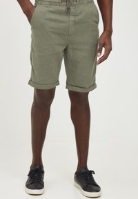 Olivenfargede shorts med rullekanter, laget av lett stoff, med elastisk midjebånd og snor samt lommer på siden.