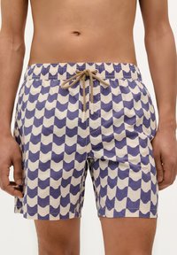 Pantaloni de baie dintr-un material ușor, cu un model de valuri în crem și bleumarin, având o talie elastică și detalii cu șnur bej.