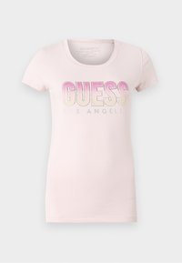 Jasnoróżowa koszulka z krótkim rękawem z napisem "GUESS" w gradientowych różowych literach oraz "LOS ANGELES" nadrukowanym poniżej na środku przodu.
