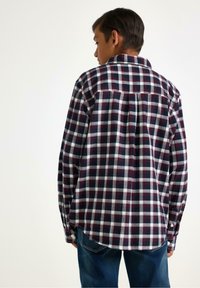 Camicia a quadri con un design in navy, rosso e bianco. Polsini con bottoni e orlo curvo. Realizzata in un tessuto morbido e traspirante.