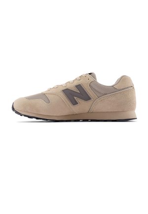 Beige New Balance sneaker met suède en mesh panelen, zwart logo aan de zijkant en zwarte rubberen zool, zijaanzicht op witte achtergrond.