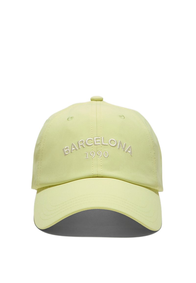 Cappellino da baseball giallo chiaro con "BARCELLONA 1990" ricamato in bianco sul davanti, visto dalla parte frontale centrale.