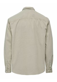 Beige pitkähihaisessa kangashirtissä, joka näkyy takaa, on napitettavat hihansuut ja klassinen kaulus valkoisella taustalla.