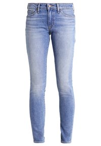 Jeans ajustados hechos de denim azul claro, con un acabado desgastado, diseño clásico de cinco bolsillos, pasadores para cinturón y botón de metal plateado.
