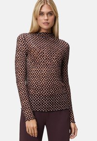 Pull à manches longues en tissu transparent à motif floral, avec un col haut, dans des teintes noir et or rose, et un design près du corps.