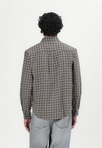 Bruine geblokte blouse met lange mouwen, knoopsluiting aan de voorkant en afgeronde zoom, gemaakt van lichte stof. De rug heeft een plooidetail.