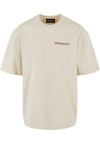 Beige bomulds t-shirt med rund hals, korte ærmer og et lille "DROPSIZE" logo i brun på venstre bryst.