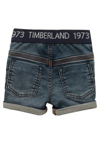 Shorts de mezclilla con una cinturilla azul oscura con "TIMBERLAND 1973" impreso, dobladillos con vuelta y dos bolsillos traseros con costuras en contraste.
