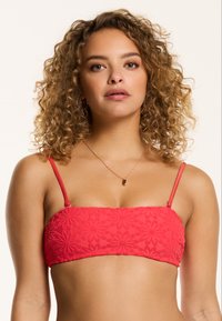 Top bikini bandeau rosso con texture floreale, spalline sottili regolabili e finitura liscia. Progettato per un look aderente e comfort.