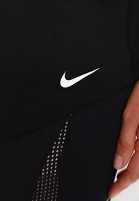 Czarne szorty sportowe z białym logo Nike, o smukłym designie i siateczkowej wstawce zapewniającej wentylację oraz kontrast tekstur.