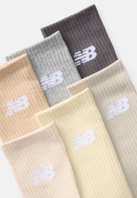 Meias de algodão caneladas nas tonalidades bege, cinza, castanho e amarelo, com um logótipo branco da New Balance em cada par.