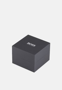 Scatola regalo rettangolare nera con finitura opaca, con il logo "BOSS" in bianco sulla superficie superiore, bordi precisi e un coperchio a cerniera.