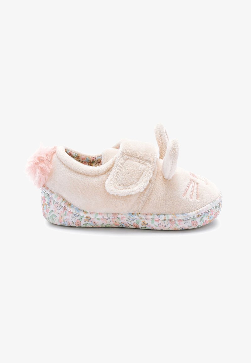 Chaussure de bébé beige douce avec des oreilles de lapin, une queue pompon rose et une semelle à motif floral, sécurisée par une bride velcro.