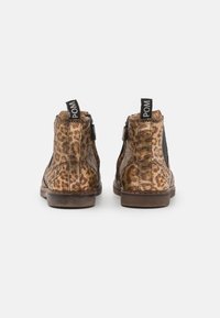 Bottines imprimées en animal marron avec une finition en suède, dotées de panneaux latéraux élastiques et d'une poignée noire à l'arrière. Semelle plate en caoutchouc.