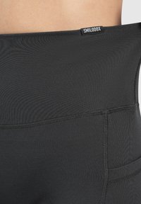 Czarne, dopasowane legginsy z gładką teksturą, wysokim stanem z metką logo i kieszenią z boku.