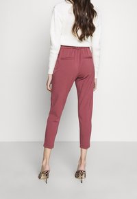 Pantaloni rosa a sigaretta con una morbida texture e una vita elastica, dotati di due tasche posteriori. Indossati con scarpe con tacco alto a stampa animale.