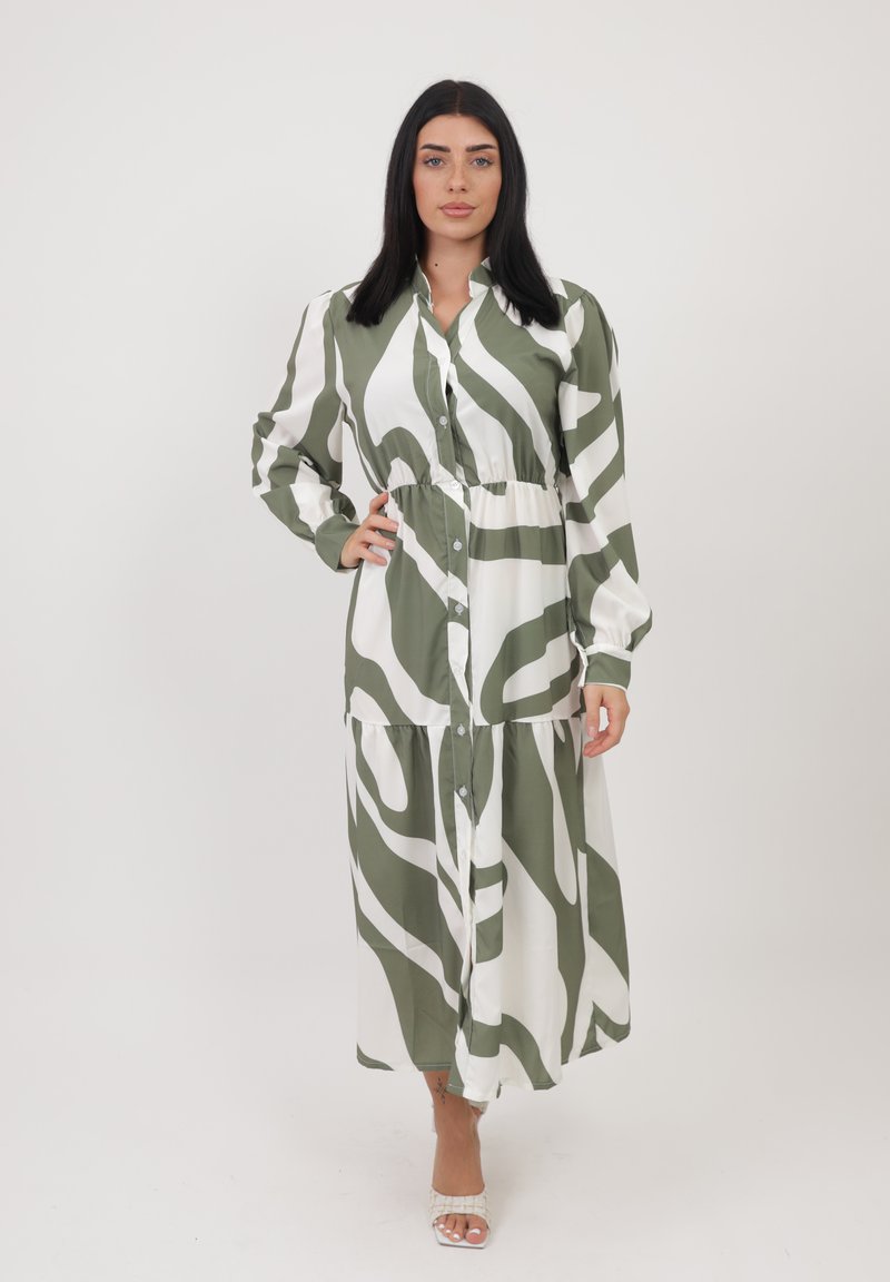 Lungo vestito con bottoni in tessuto leggero, caratterizzato da un motivo astratto verde e bianco. Ha maniche lunghe e un design a gonna a strati.