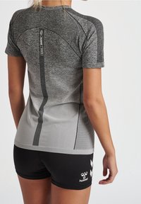 Szara sportowa koszulka z krótkim rękawem, z teksturowanym wzorem i czarnymi paskami, zestawiona z czarnymi szortami z białym logo.