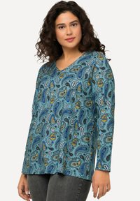Langärmlige taubenfarbene Bluse mit einem Paisleymuster in Blau, Gelb und Schwarz. Verfügt über ein V-Ausschnitt-Design und einen weichen, strukturierten Stoff.