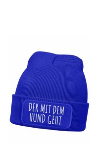 Blue knit beanie with a ribbed texture and a folded cuff, featuring a rectangular patch with white text: "DER MIT DEM HUND GEHT."