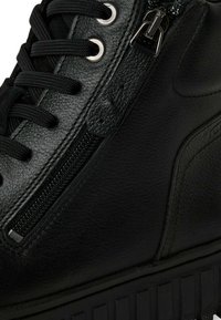 Baskets montantes noires avec une tige en cuir lisse, fermeture à lacets, zip sur le côté et semelle en caoutchouc avec des rainures verticales.