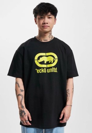 Schwarzes Baumwoll-T-Shirt im Oversized-Schnitt, mit einem leuchtend gelben Logo und grafischem Design auf der Vorderseite. Minimalistischer Stil, kurze Ärmel.
