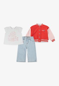 Rød og pink varsity-jakke med hvid kant, en hvid t-shirt med et pink blomsterdesign, og lyseblå brede denim-jeans.